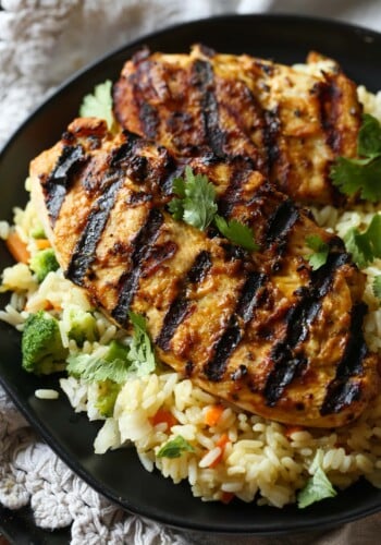 Grilled peanut butter chicken is served over a bed of rice and veggies.