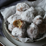 Rice fritters coated in powdered sugar in a bowl