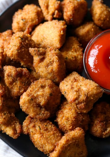 Spicy homemade chicken nuggets on a plate next to dipping sauce.