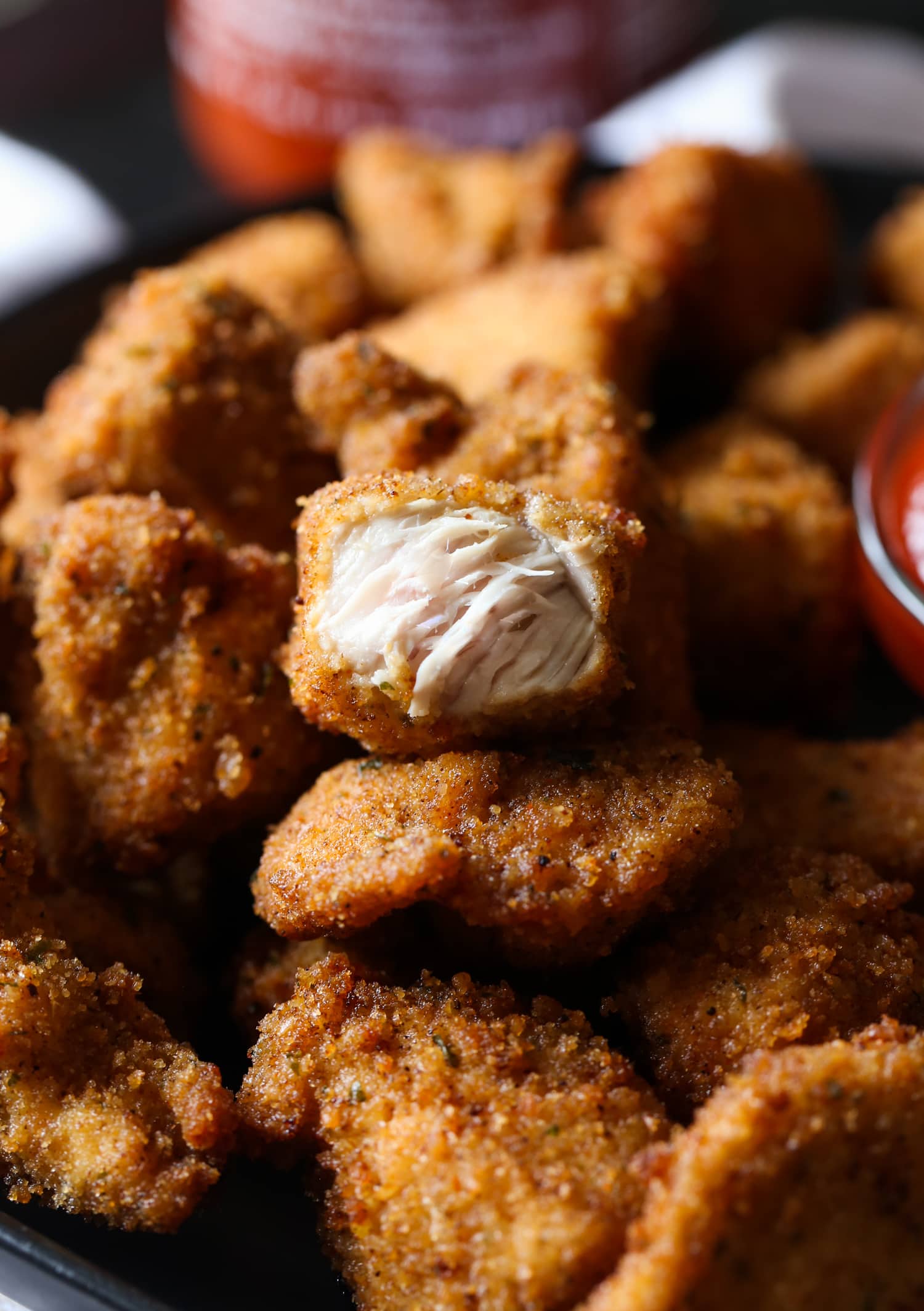 A plate full of homemade spicy nuggets, with one chicken nugget cut open to reveal tender and juicy insides.