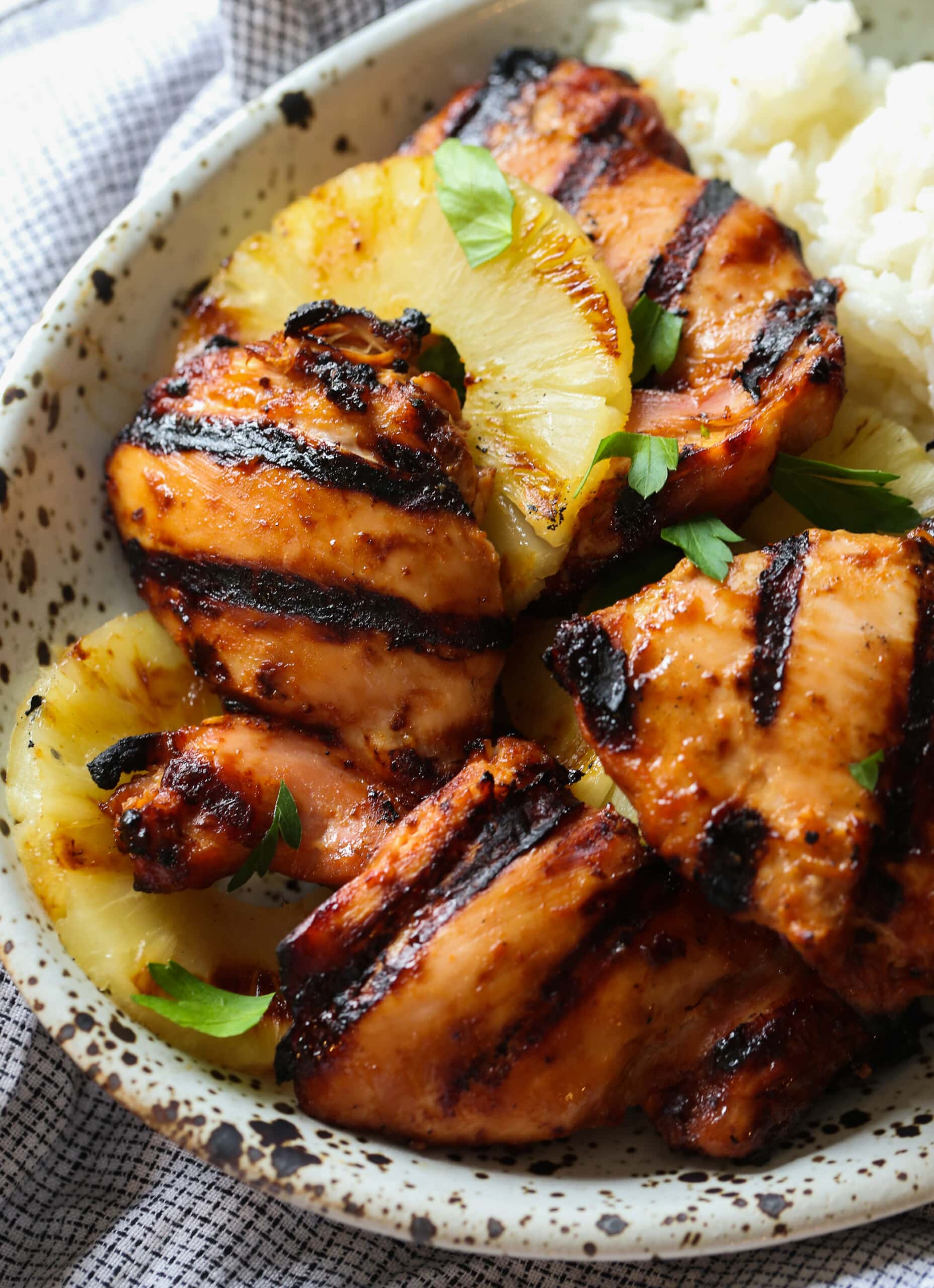 Hawaiian Huli Huli chicken served in a bowl with grilled pineapple over rice.