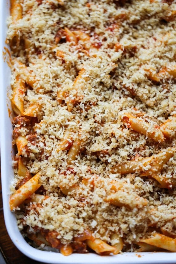 Parmesan cheese and breadcrumbs are sprinkled over top of saucy mostaccioli pasta.