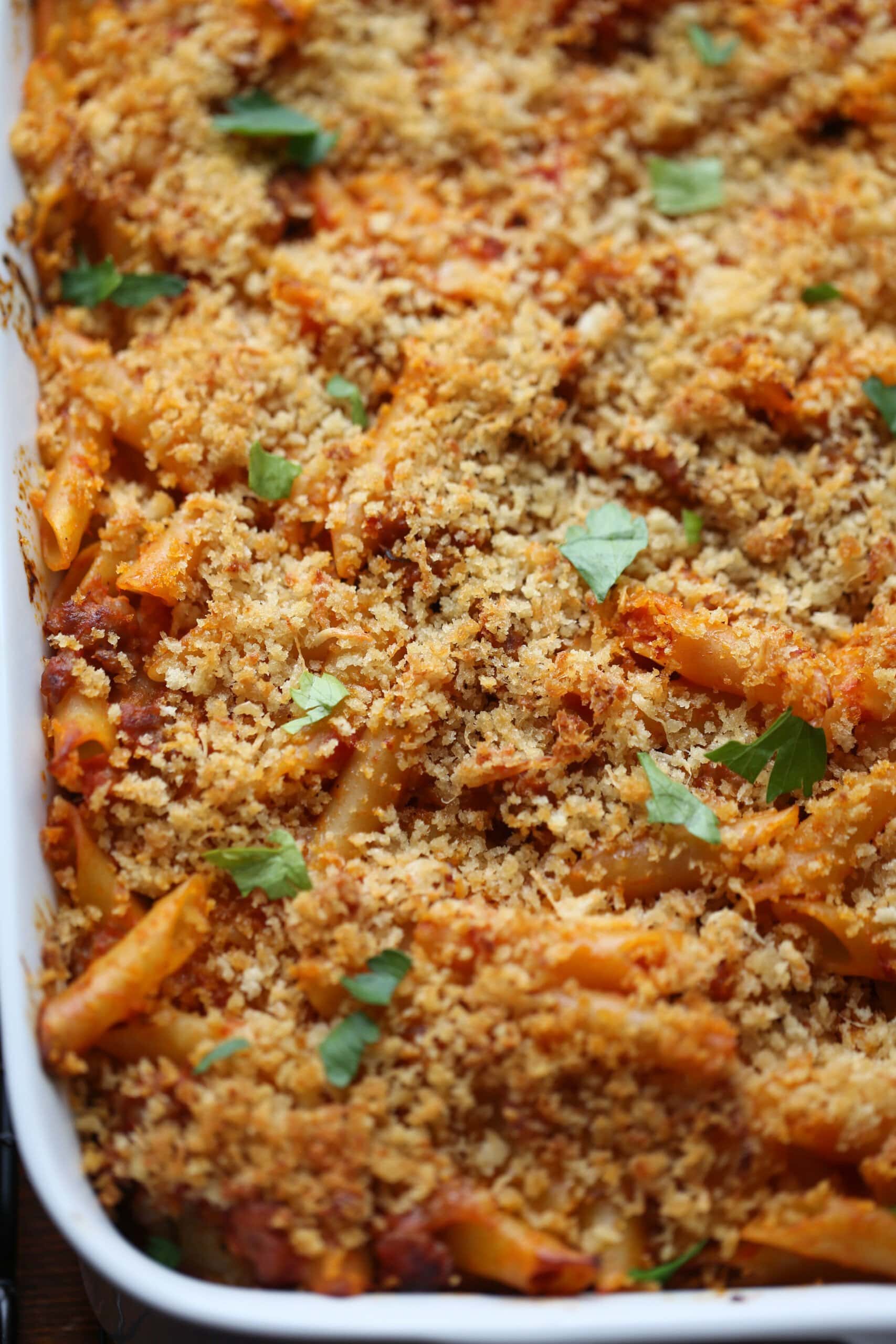 Close up of baked mostaccioli topped with parmesan cheese and breadcrumbs.