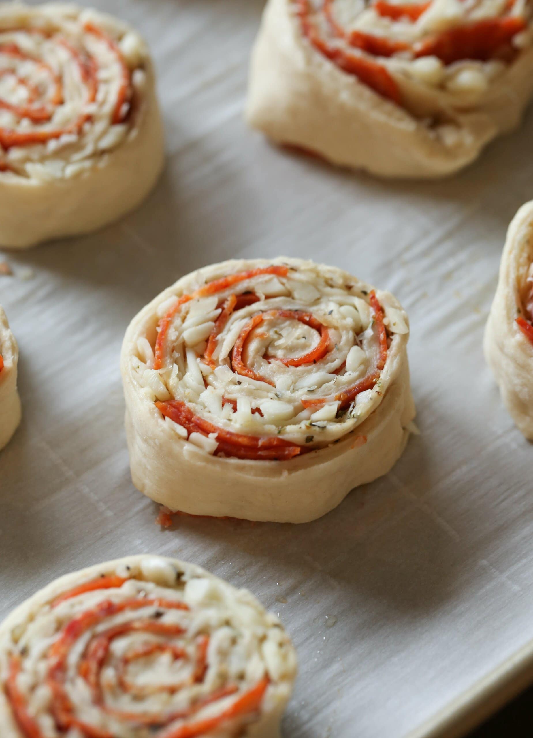 Unbaked pizza rolls laid out on a parchment lined baking tray.