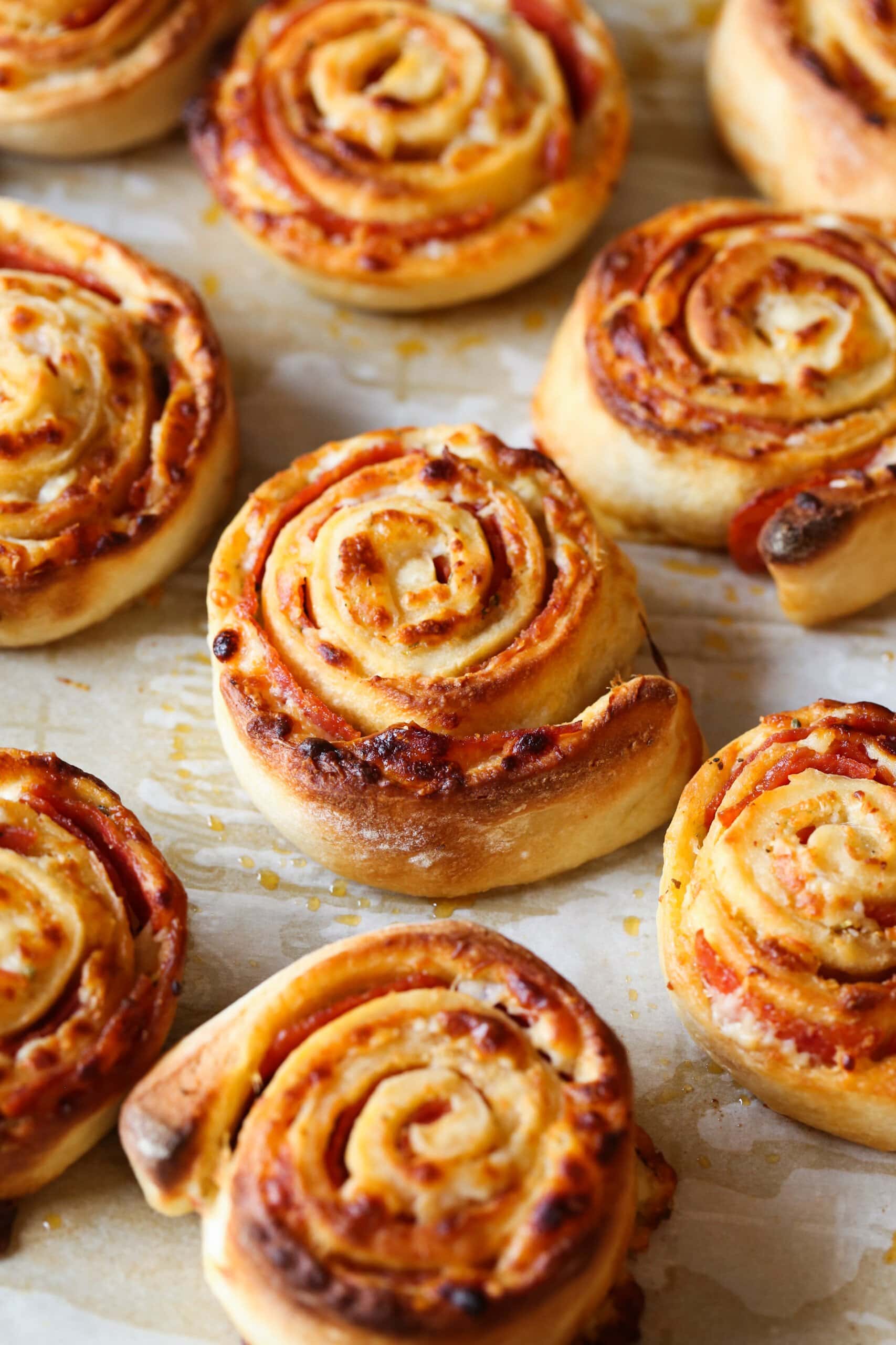 Golden baked pepperoni pizza rolls on parchment paper.