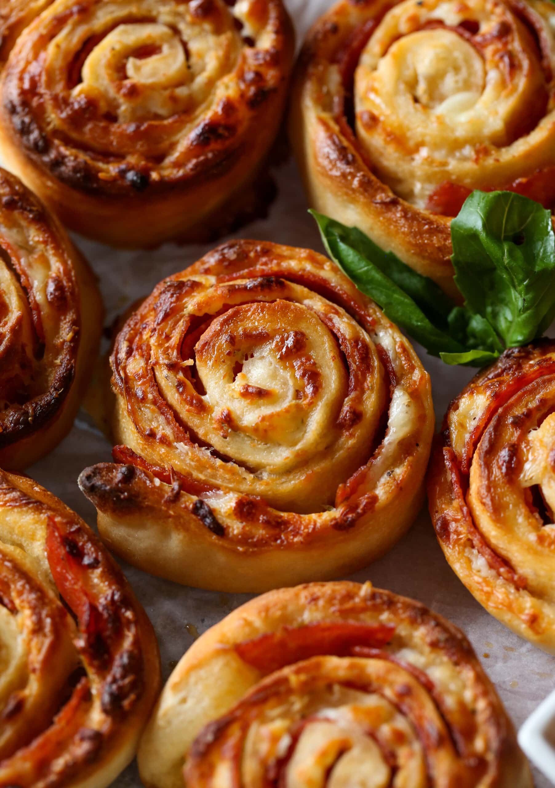 Baked pizza rolls with a garnish of basil leaves.