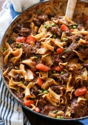 Beef and noodles cooked in a dish with carrots and peas
