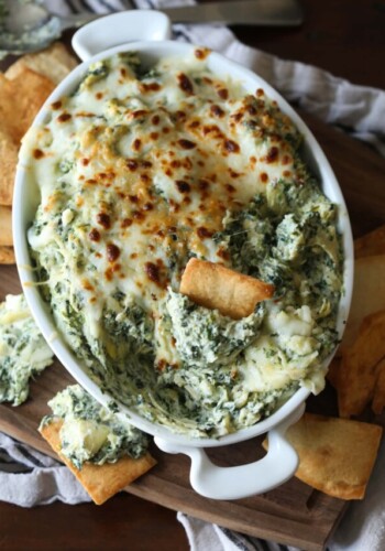 A pita chip stuck in the center of creamy spinach and artichoke dip.