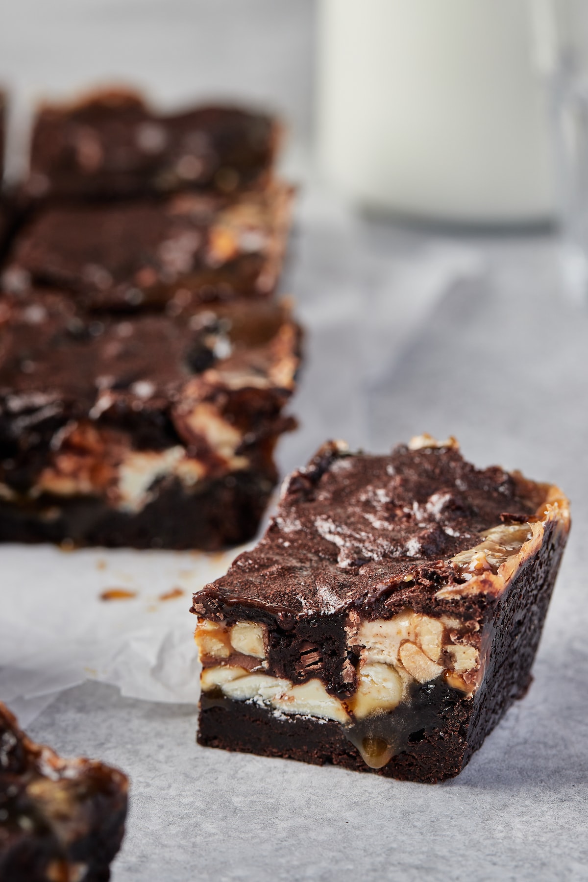 A Snickers brownie in the foreground with the rest of the brownies in the background.