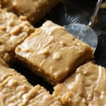 A slice of moist peanut butter sheet cake is lifted with a spatula.