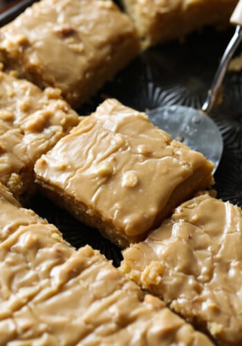 A slice of moist peanut butter sheet cake is lifted with a spatula.