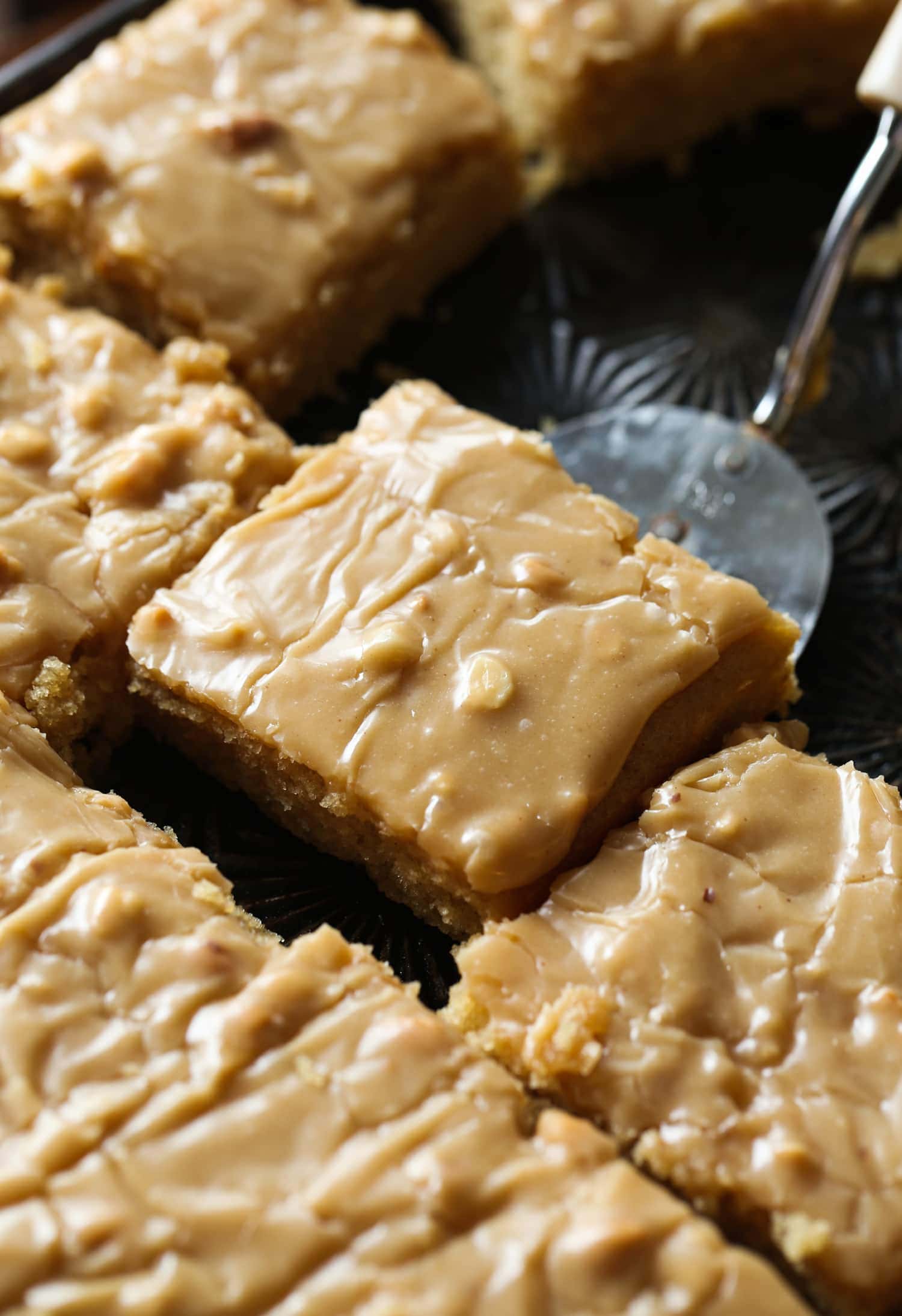 A slice of moist peanut butter sheet cake is lifted with a spatula.