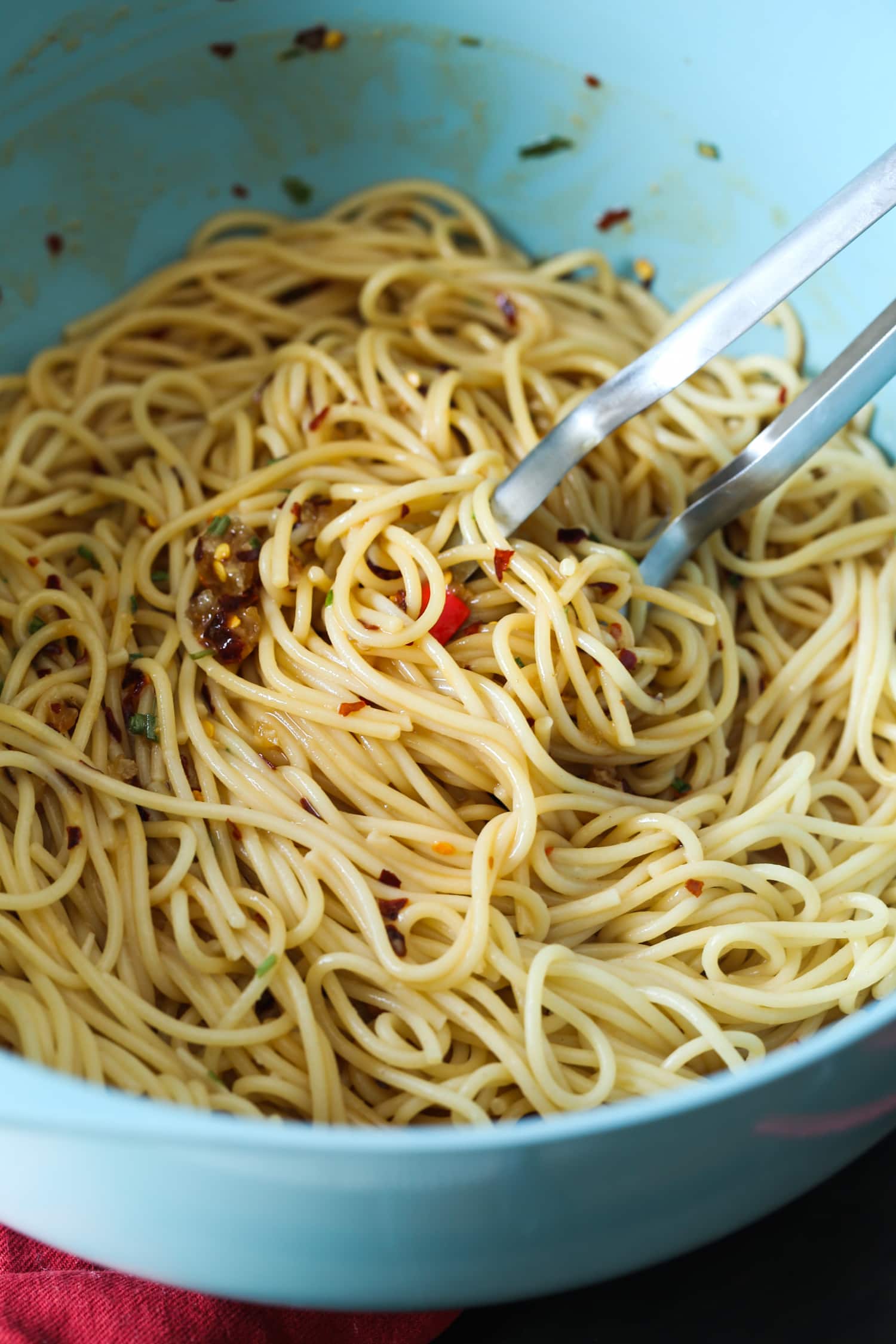 Tongs are used to toss linguine in spicy sesame peanut sauce.