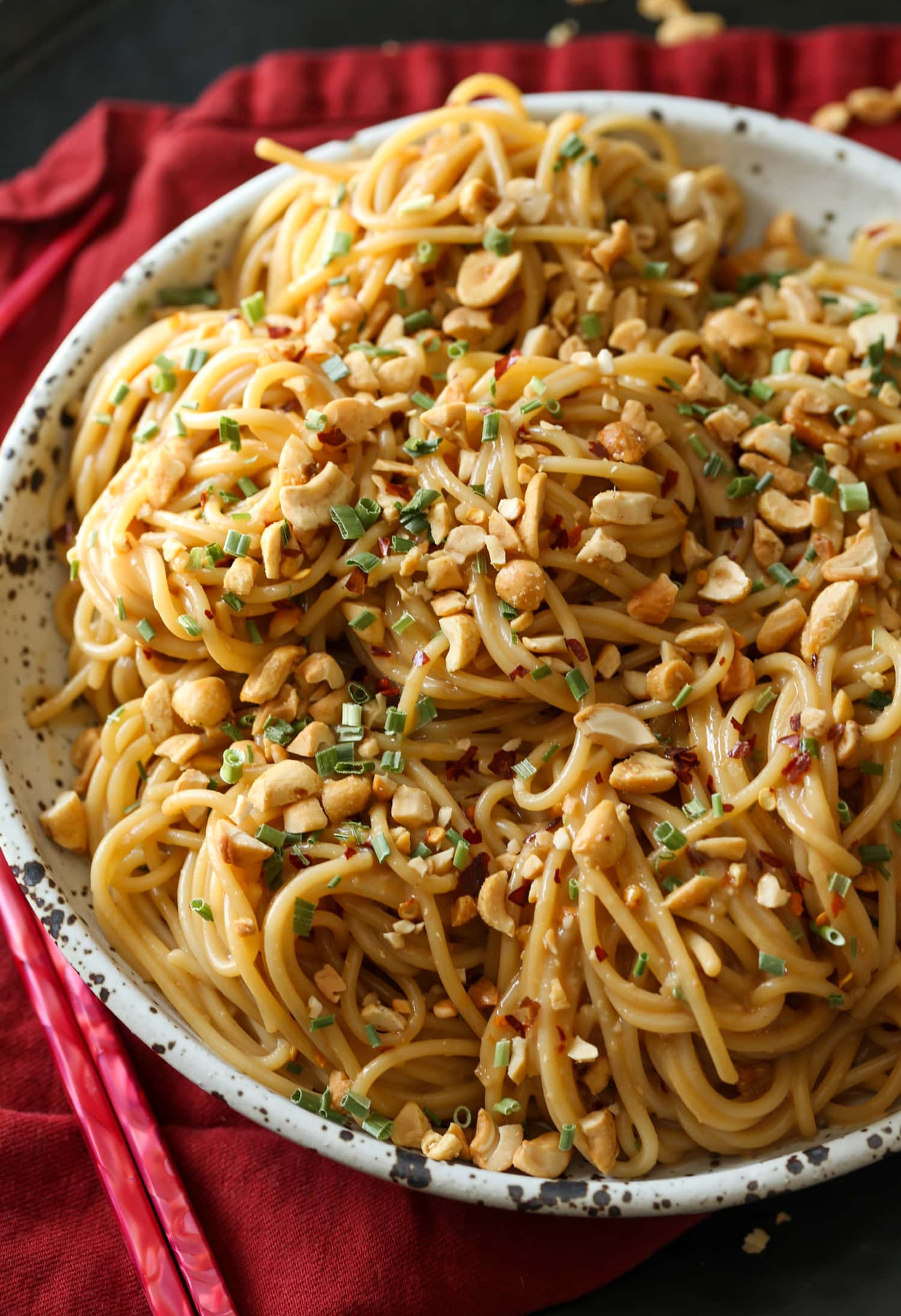 A bowl of spicy sesame noodles topped with crushed peanuts and cilantro.