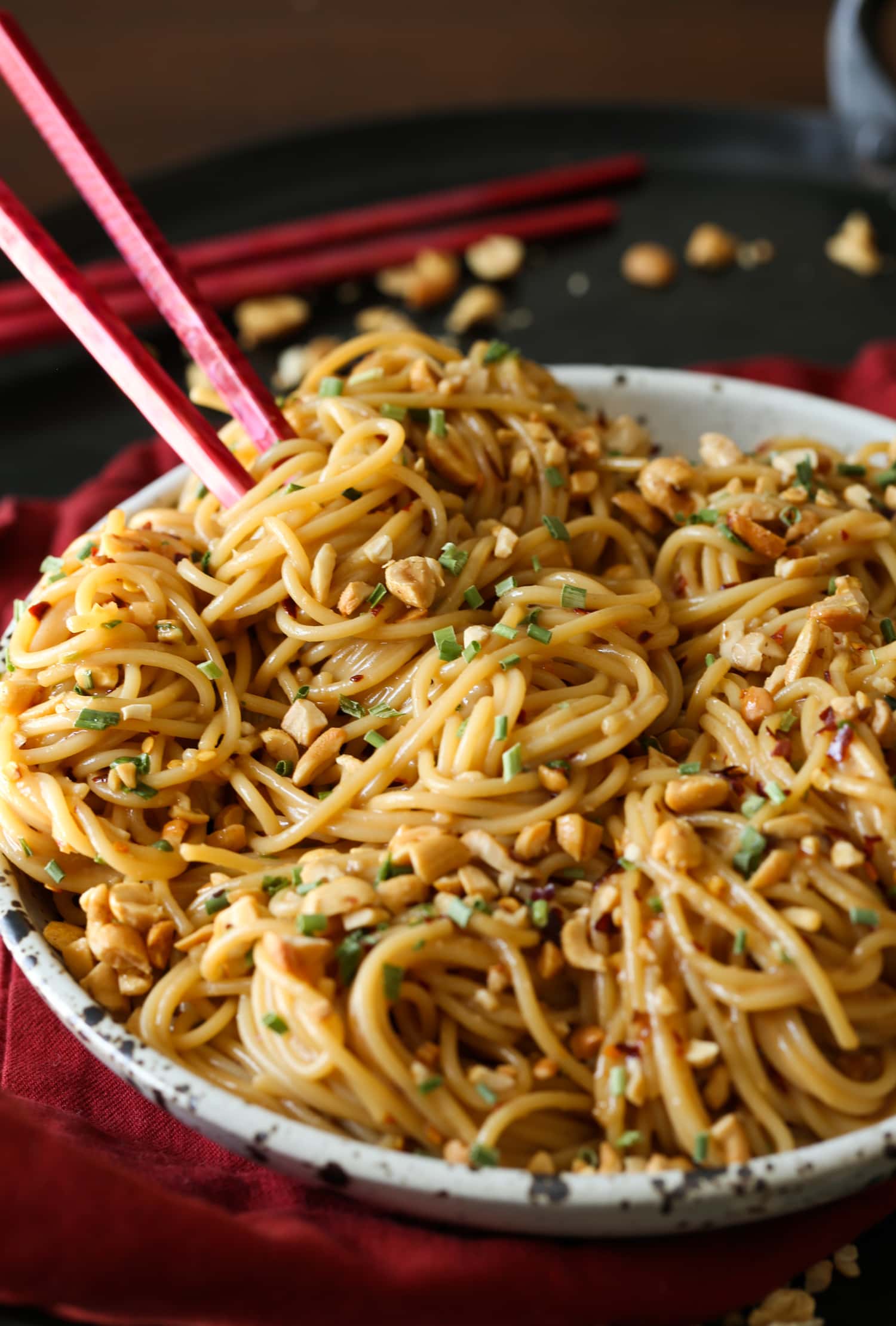 A bowl of spicy sesame noodles with chopsticks.