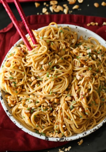 A bowl of spicy sesame noodles with chopsticks.
