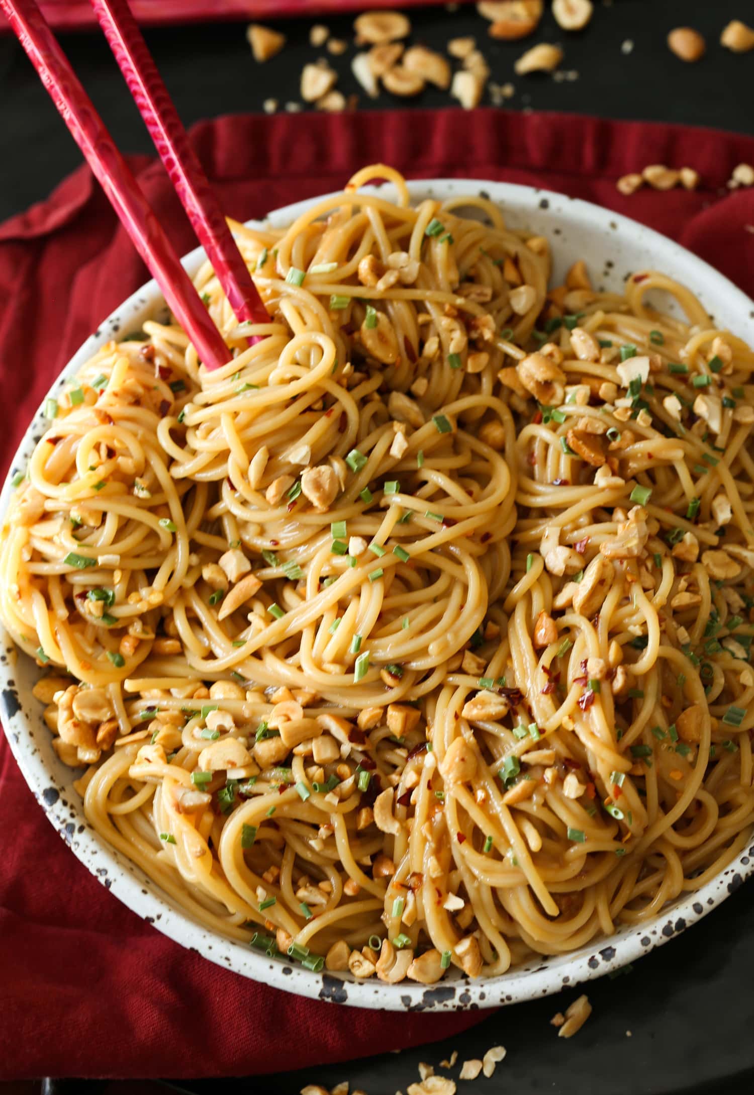 A bowl of spicy sesame noodles with chopsticks.