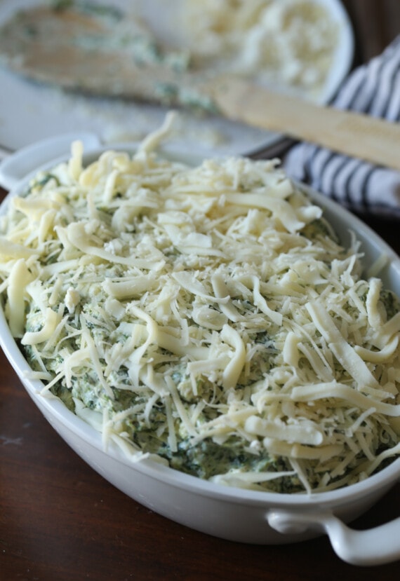 Spinach and artichoke dip topped with a layer of shredded cheese.