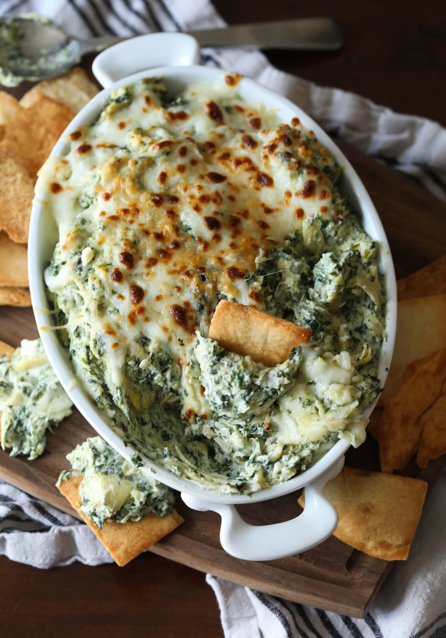 A pita chip stuck in the center of creamy spinach and artichoke dip.