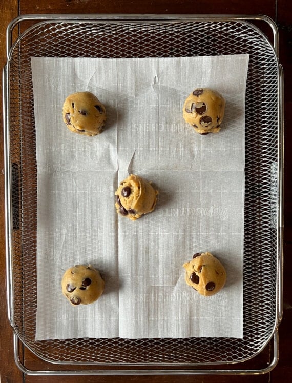 cookie dough on an air fryer basket lined with parchment paper