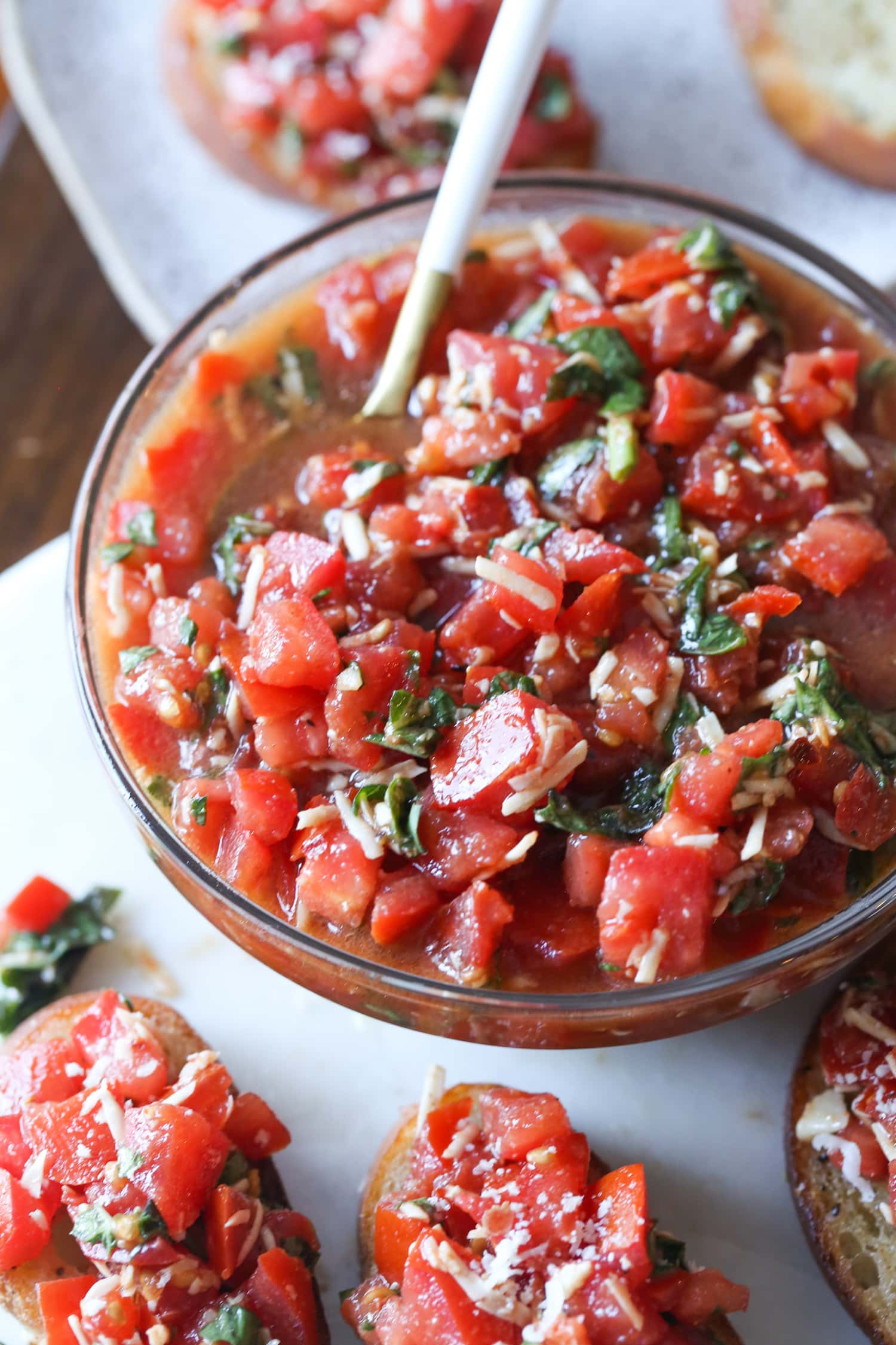 A bowl of bruschetta surrounded by bruschetta toasts.