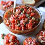 A bowl of bruschetta surrounded by bruschetta toasts.