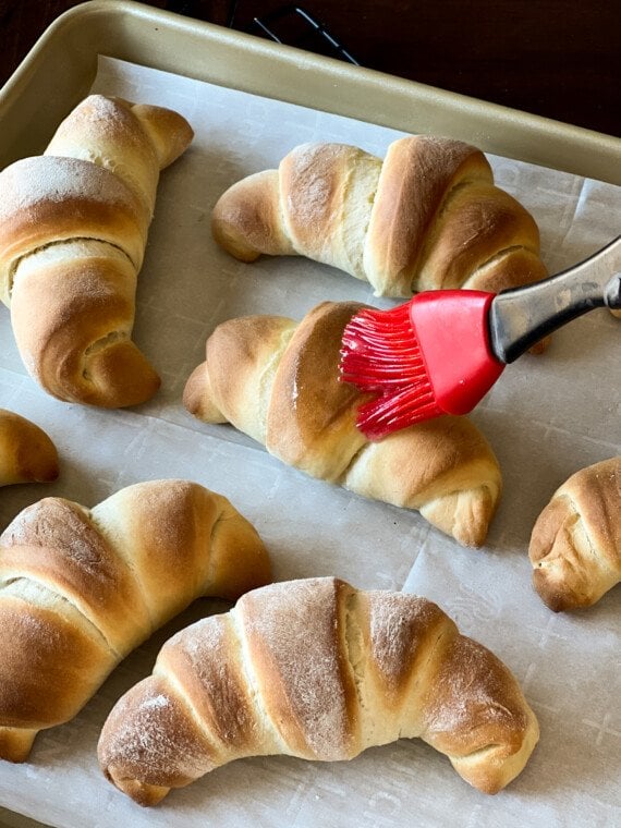 Baked crescent rolls are brushed with melted butter.