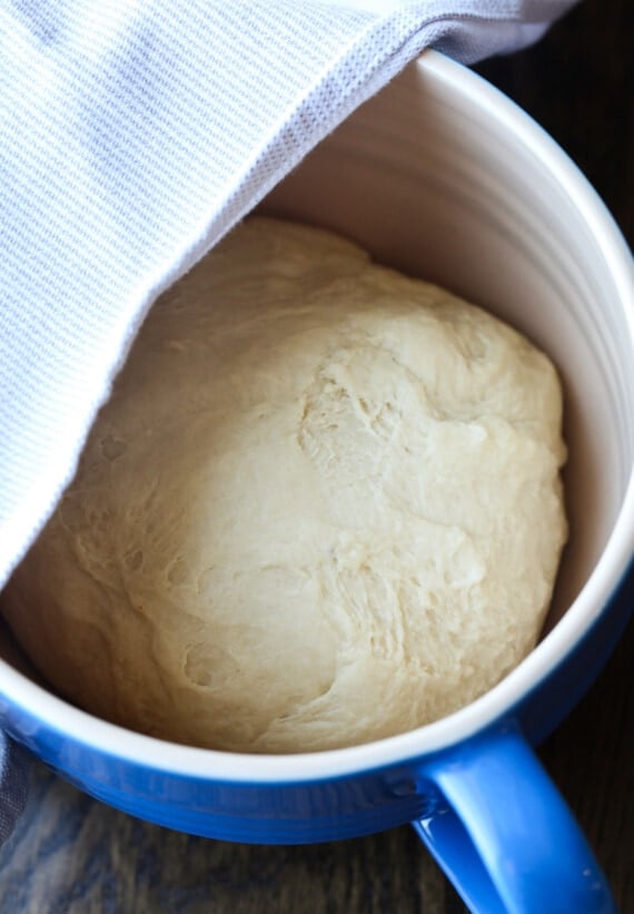 Crescent roll dough in a bowl partially covered by a cloth.