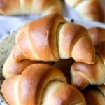 An assortment of golden baked crescent rolls on a plate.