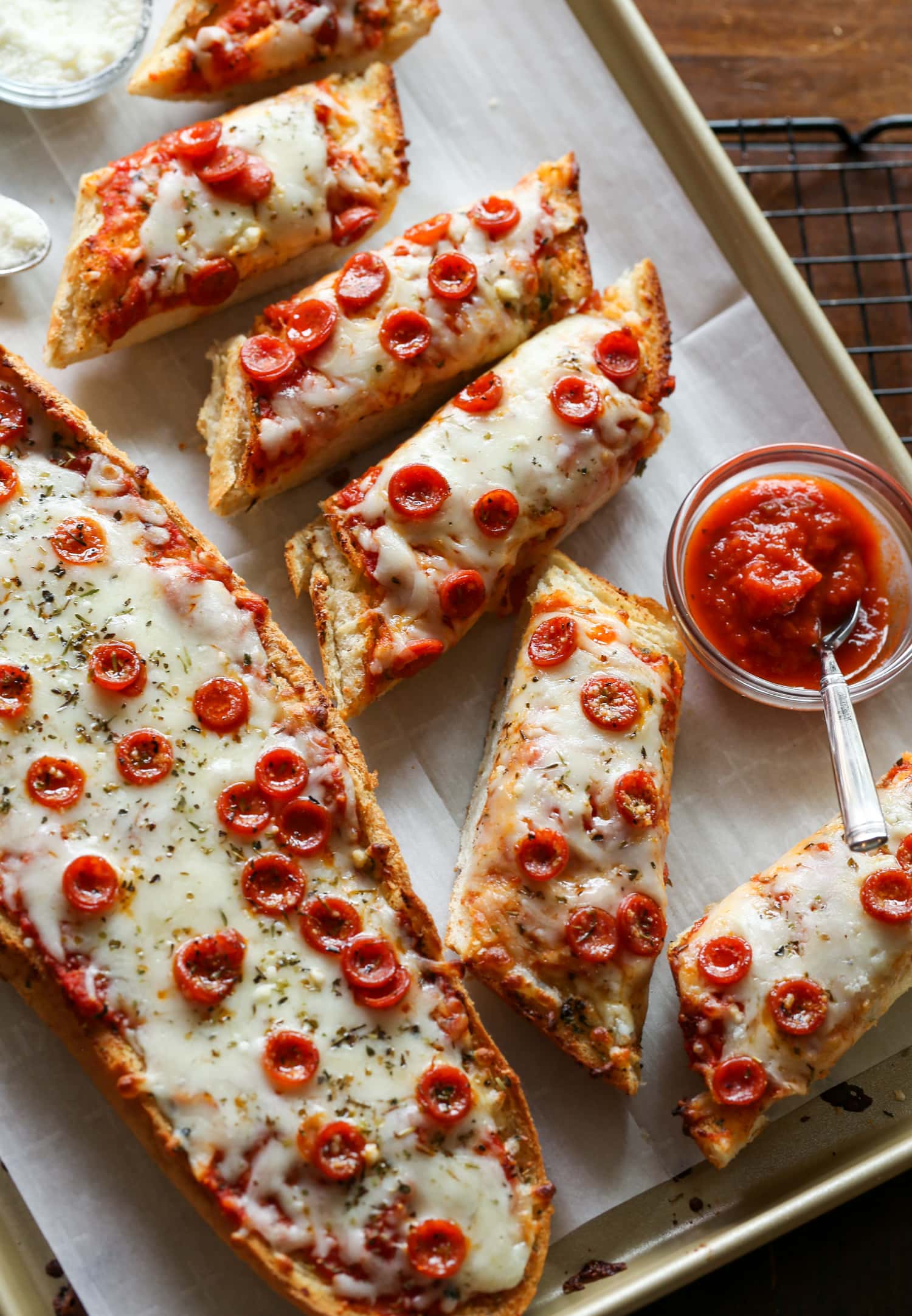 French bread pizza cut into individual slices on a platter, next to dipping sauces.