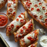 French bread pizza cut into individual slices on a platter, next to dipping sauces.