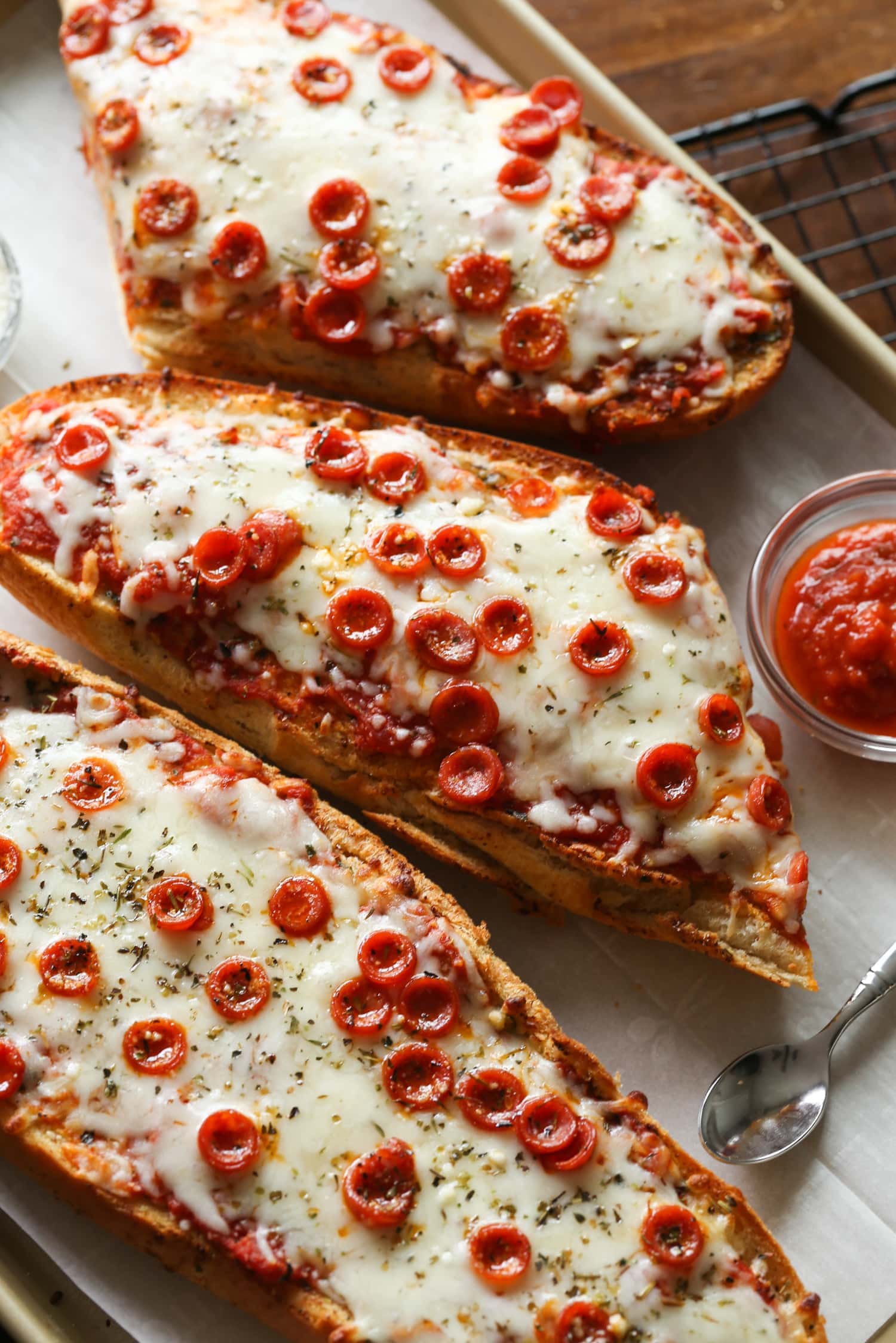 Three French bread pizzas on a platter.