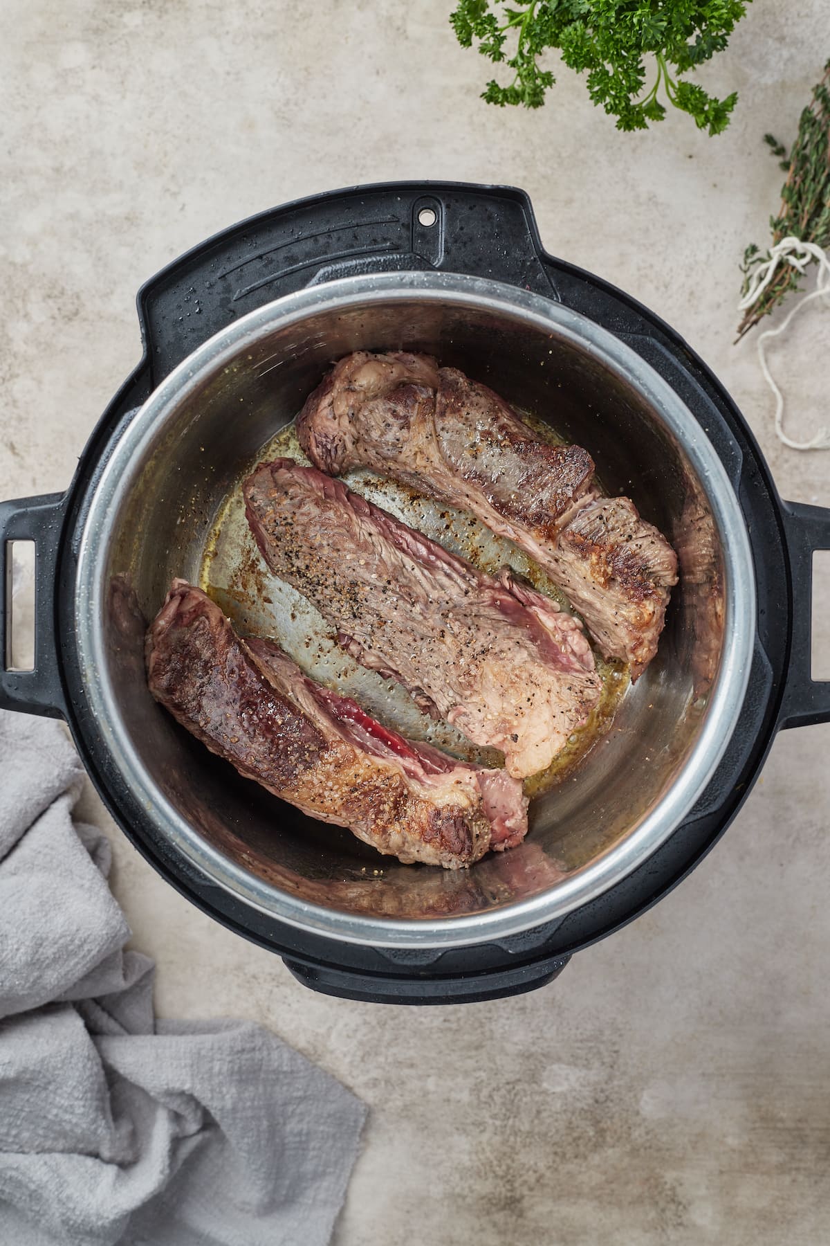 Seasoned beef short ribs are seared in the bowl of the Instant Pot.