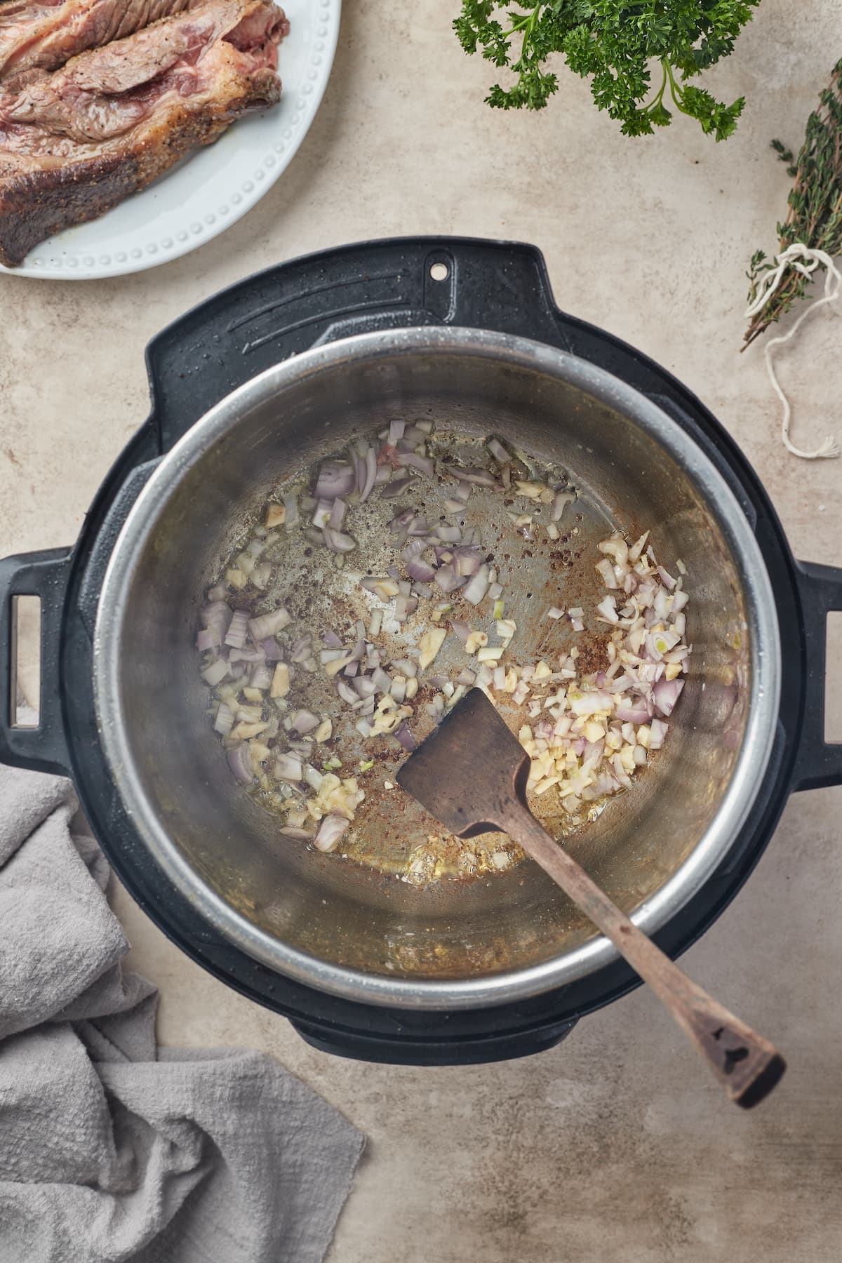 Onions and garlic are sauted in the bowl of an Instant Pot.