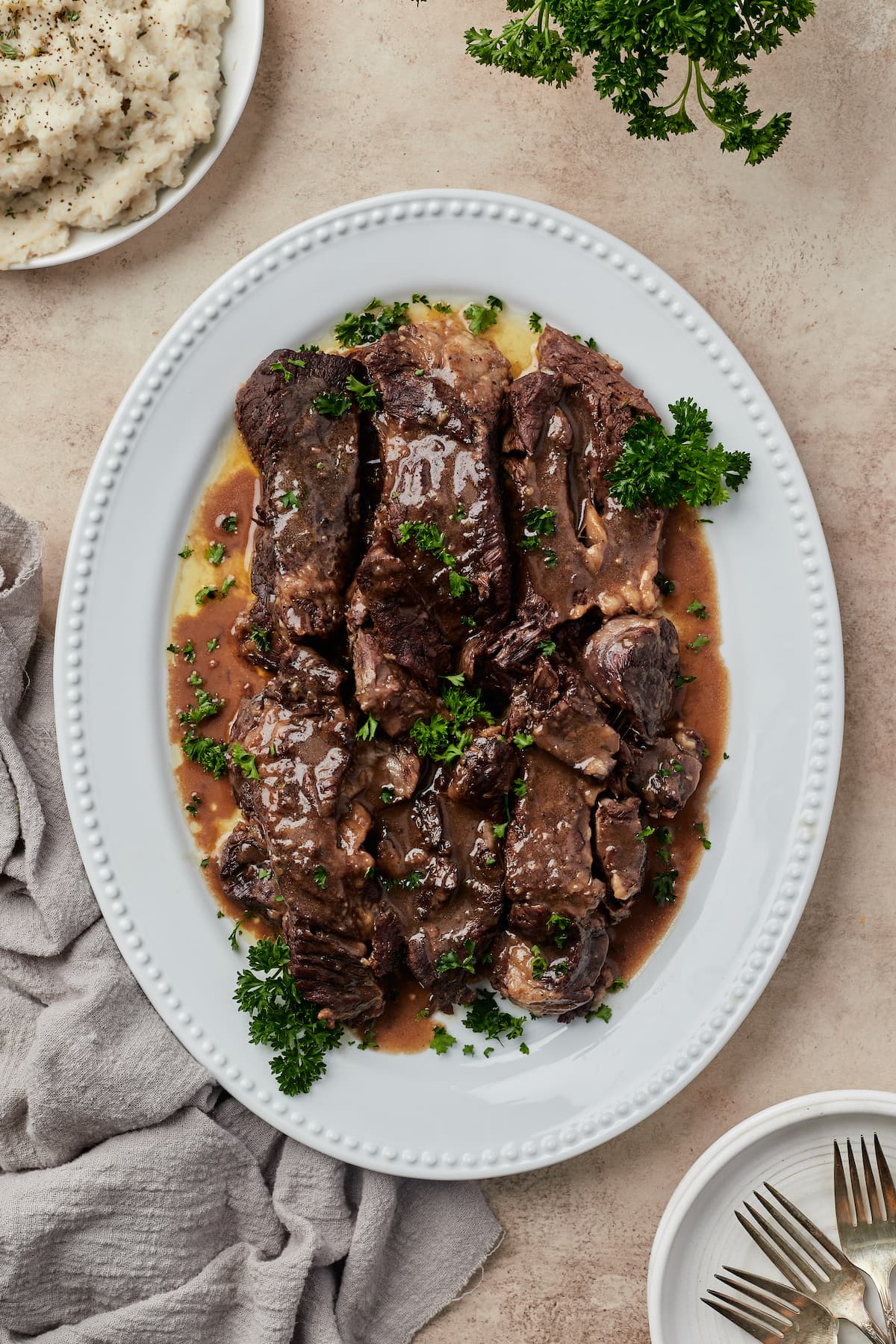 Top view of juicy beef short ribs covered in red wine sauce on a white dish.