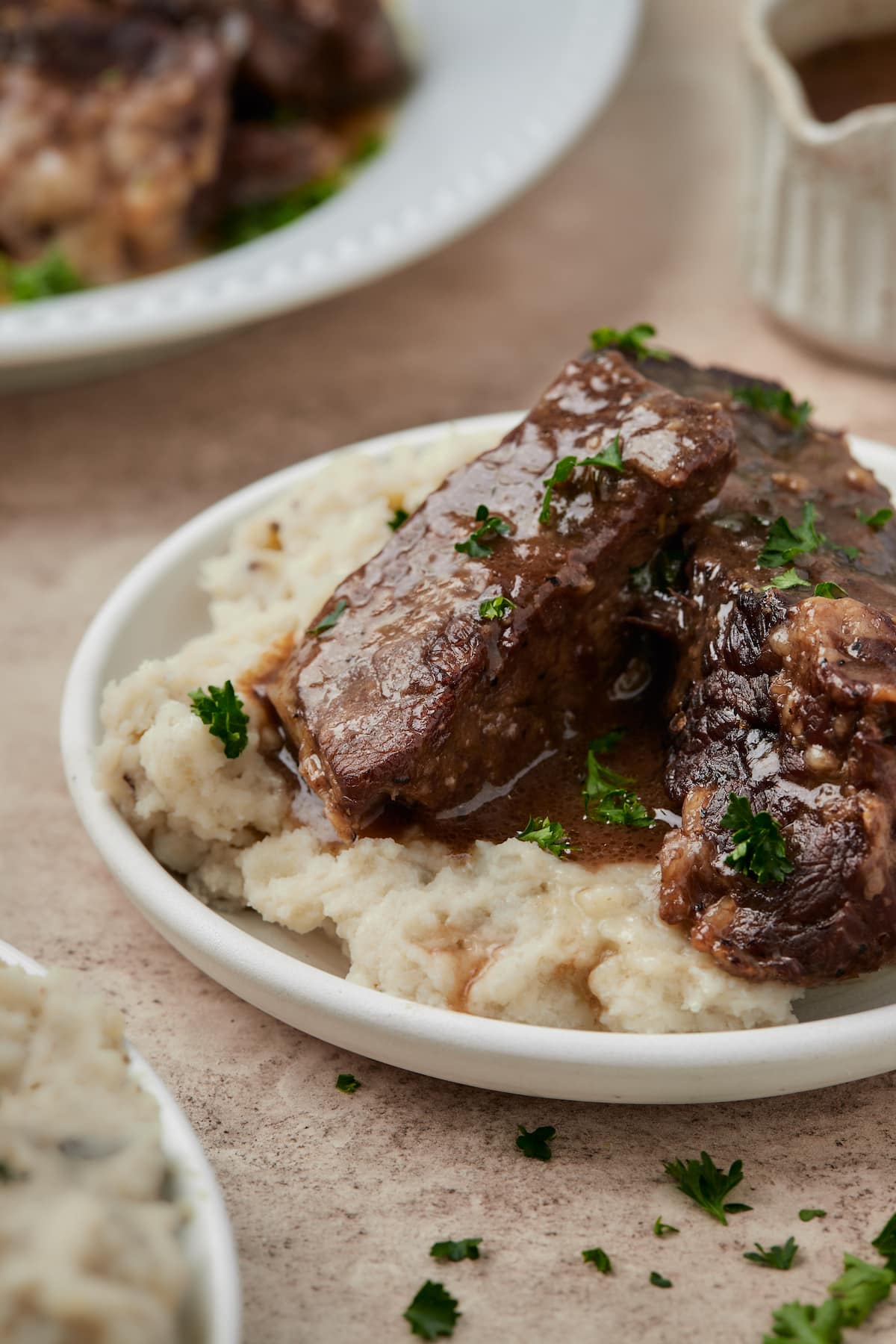 Instant Pot short ribs served in a bowl over mashed potatoes, drizzled in red wine sauce.