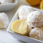 A small bowl of white chocolate lemon truffles, with one truffle cut in half.