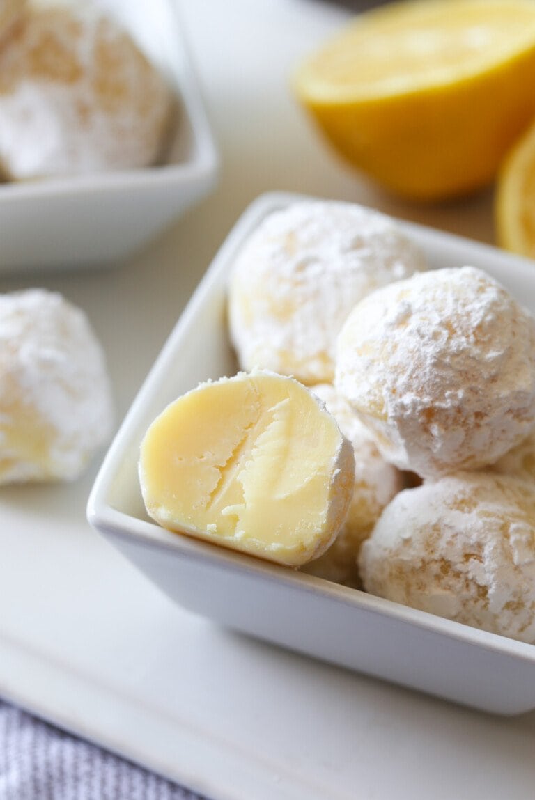 A small bowl of white chocolate lemon truffles, with one truffle cut in half.