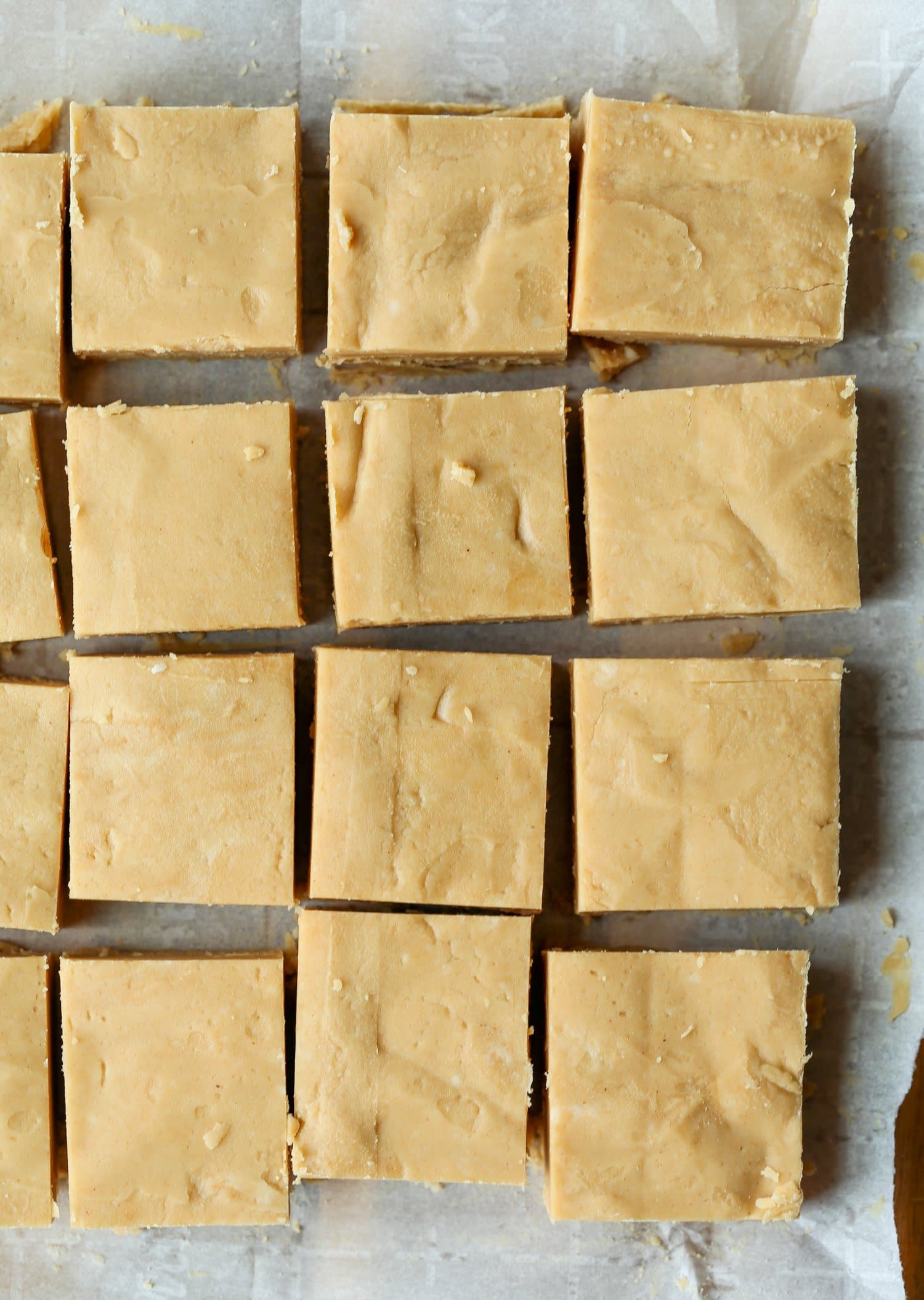 Top view of peanut butter fudge on parchment paper cut into squares.