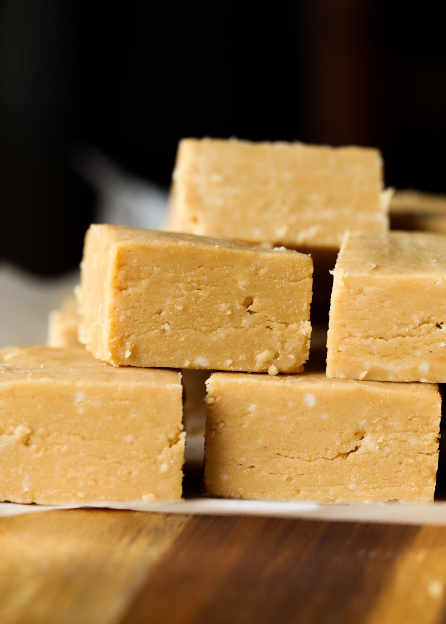 Stack of peanut butter fudge squares on parchment paper.