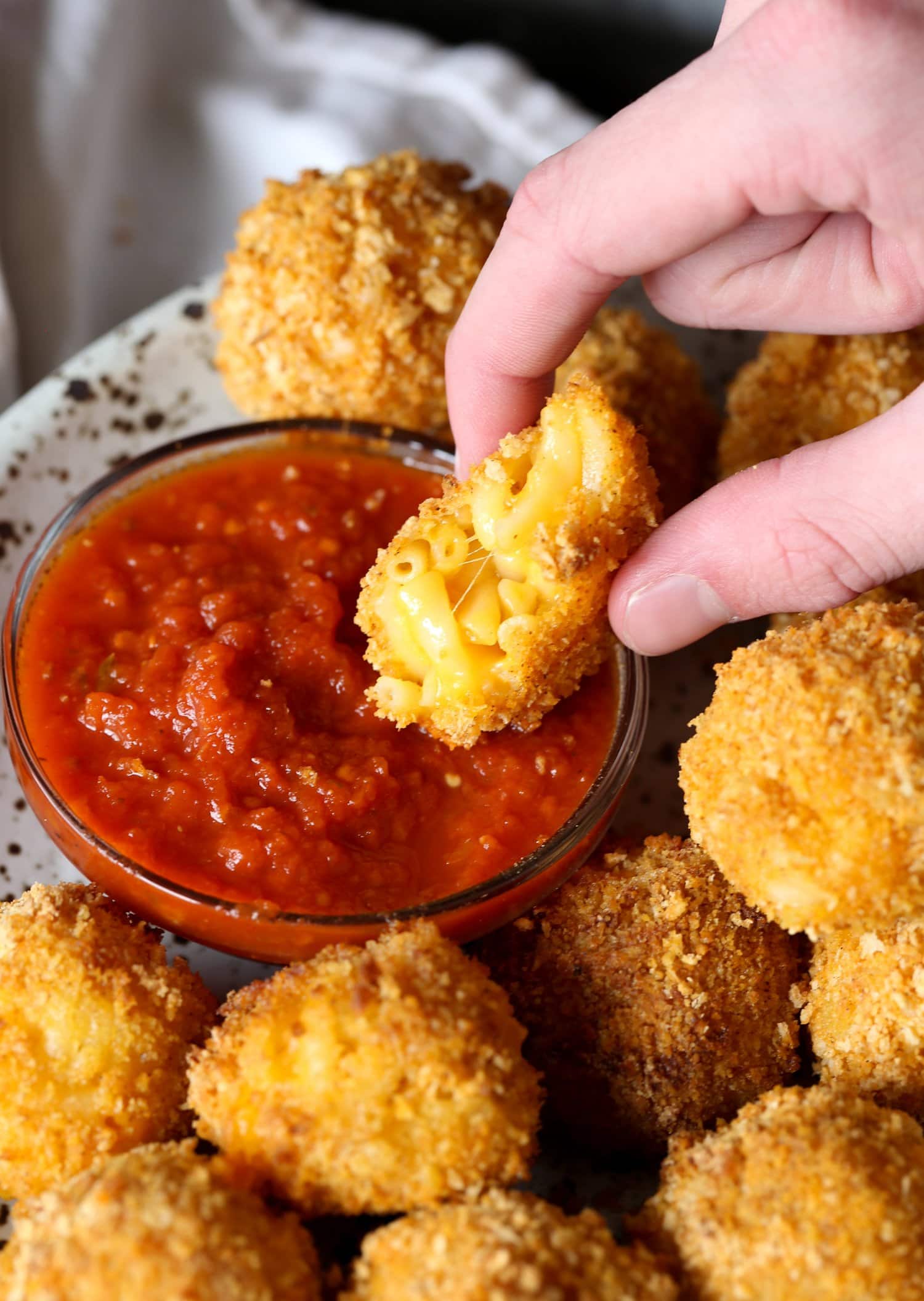 dipping fried mac and cheese balls in marinara sauce