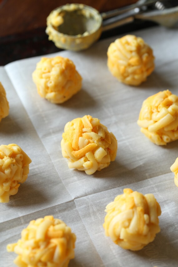 frozen mac and cheese balls on a parchment lined baking sheet