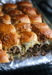Philly cheesesteak sliders in a baking dish with one row missing.