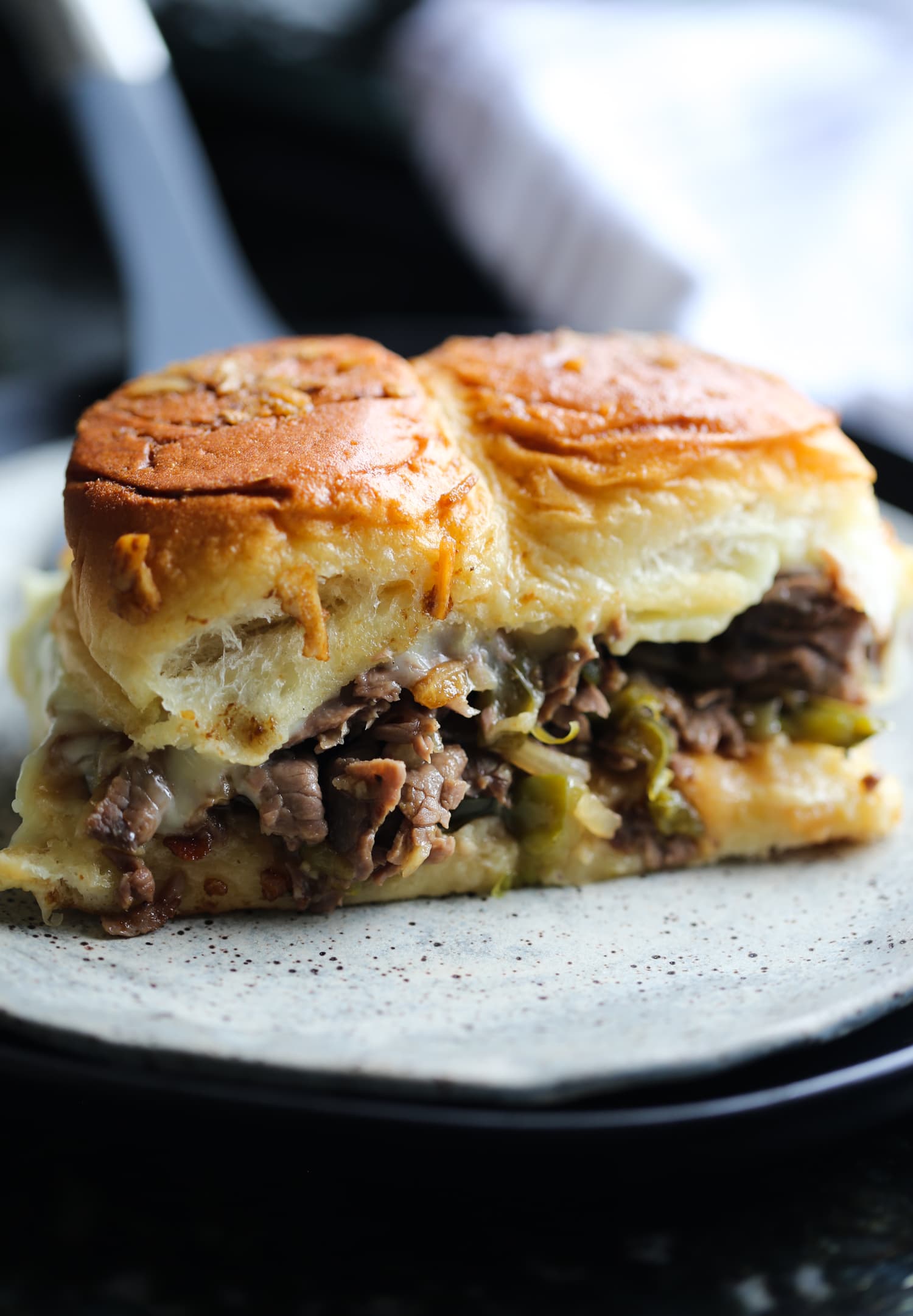 Two Philly cheesesteak sliders on a plate.