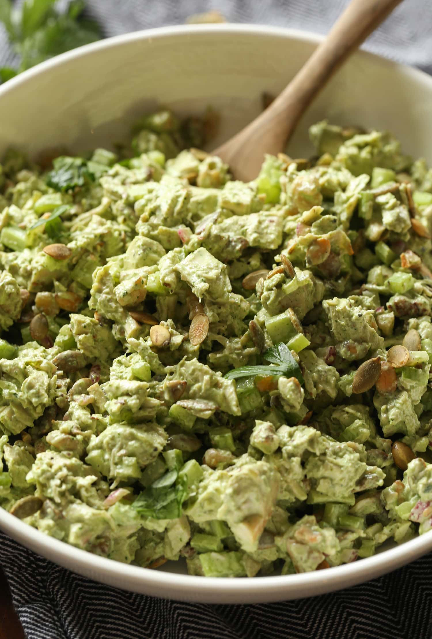 Green goddess chicken salad in a large bowl with a wooden spoon.