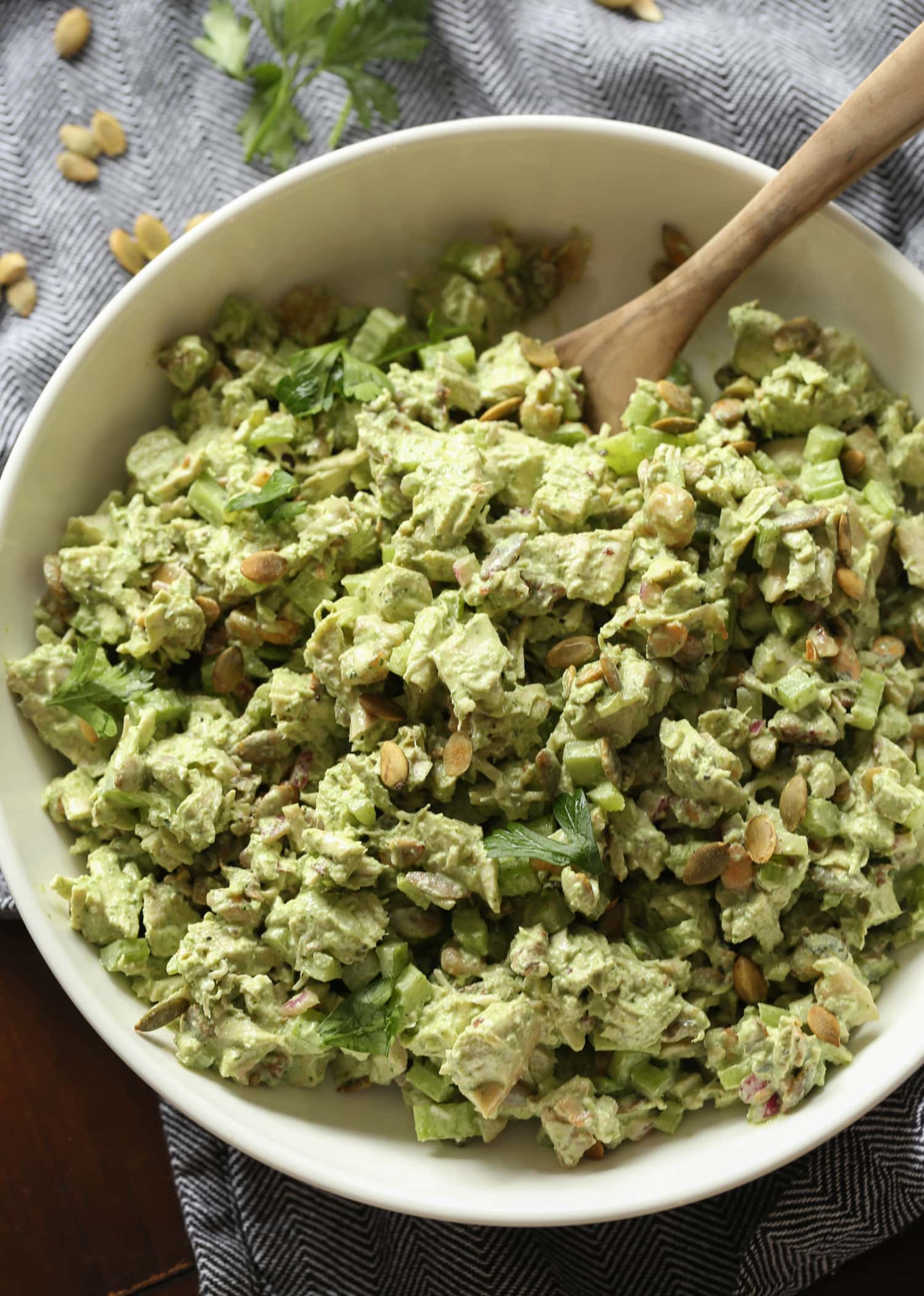 Top view of a green goddess chicken salad in a large bowl with a wooden spoon.