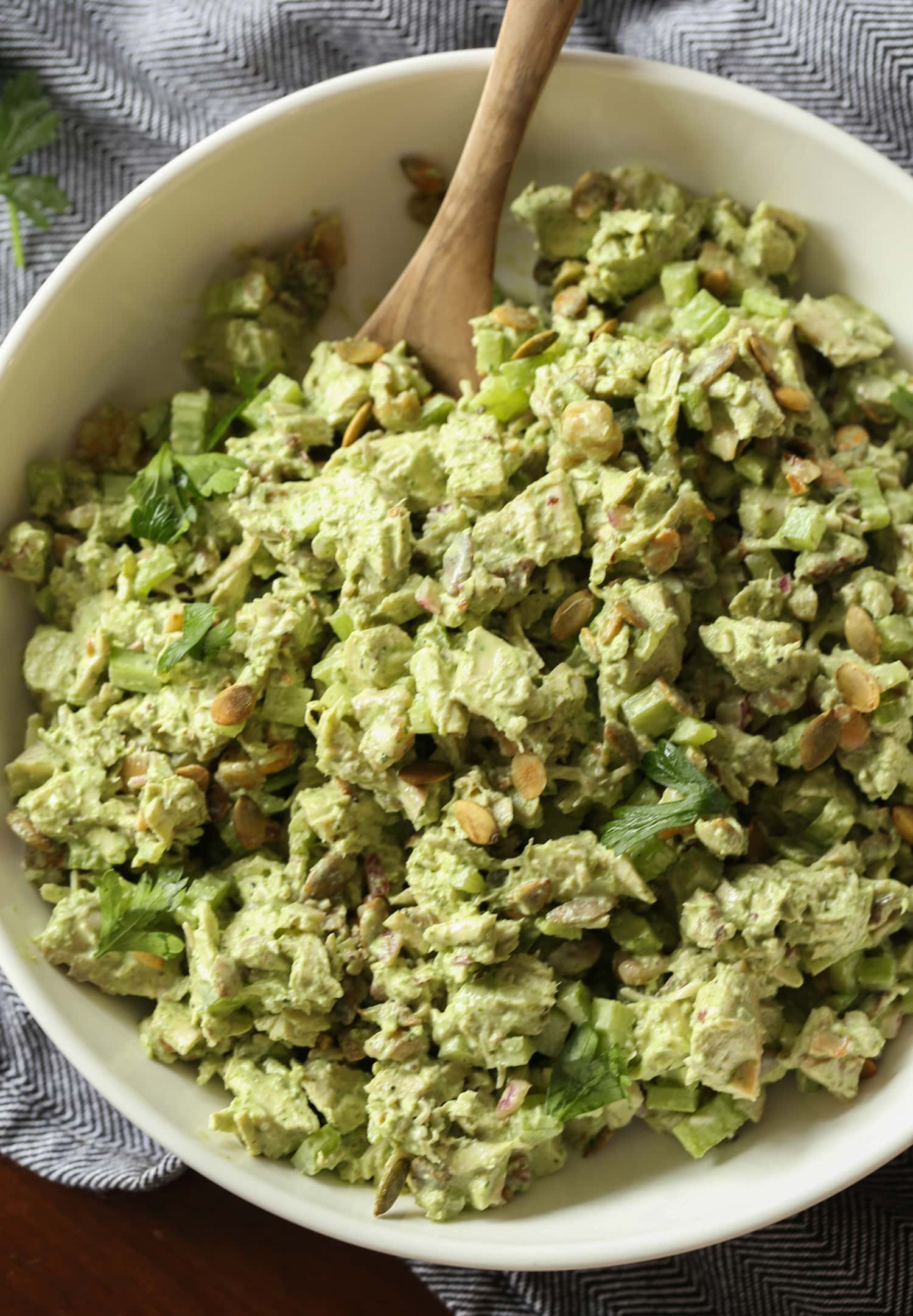 Green goddess chicken salad in a large bowl with a wooden spoon.