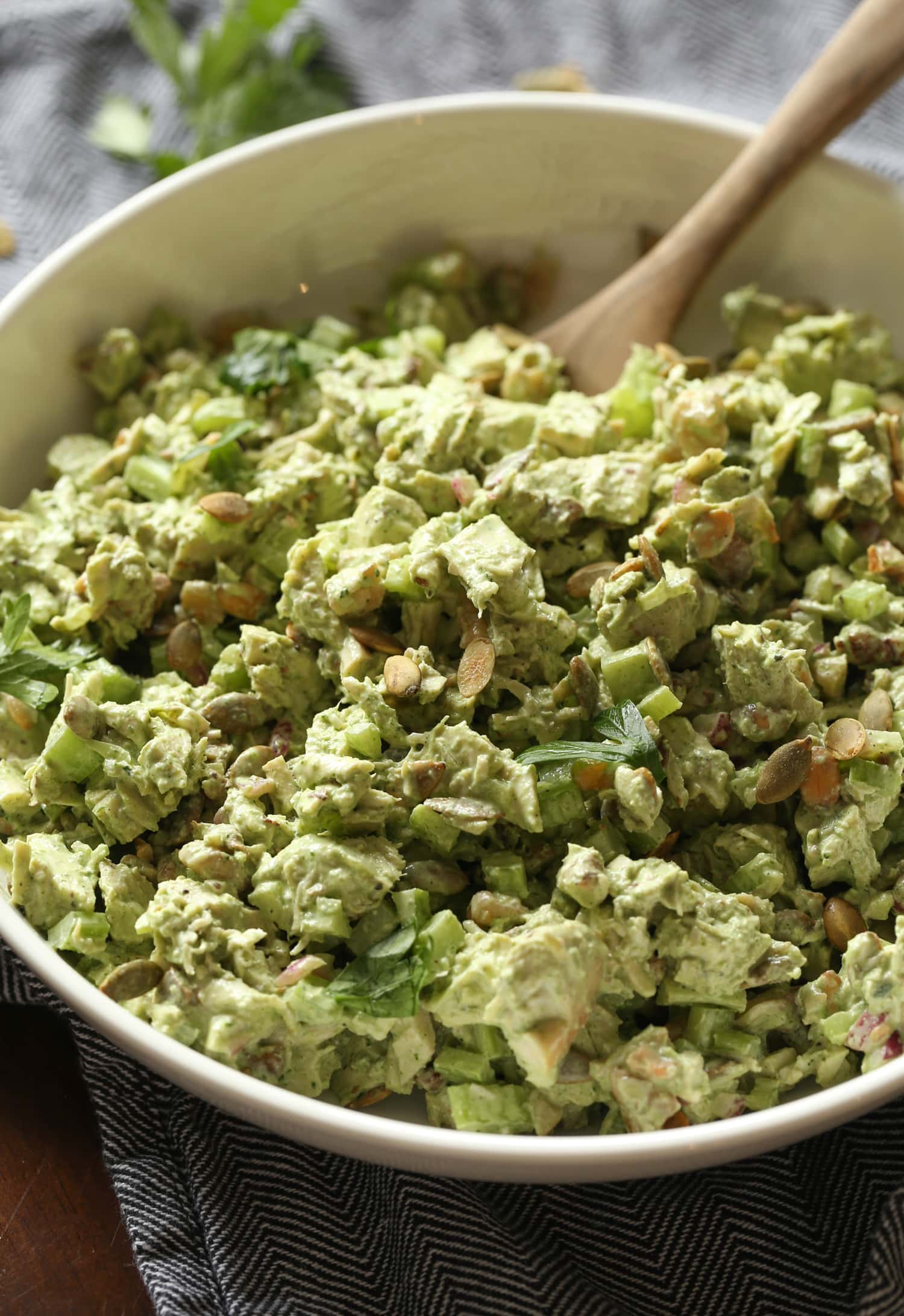 Green goddess chicken salad in a large bowl with a wooden spoon.