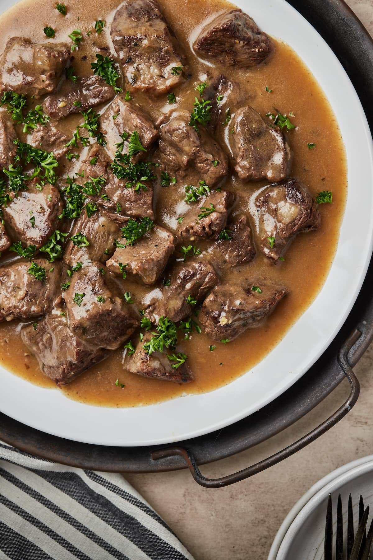 Top view of cubed beef covered with gravy on a round serving dish.