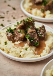 Instant Pot cubed beef and gravy served over a bed of mashed potatoes on a plate.
